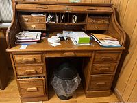 Front view of oak roll-top desk with roll top open, showing desktop surface, drawers, and interior cubbies