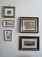 View of the five framed art pieces hanging on the wall showing variations in frame colors and artwork themes.