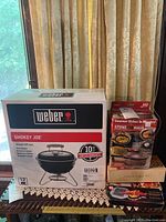 Box of Weber Smokey Joe charcoal grill, 14-inch model with a 10 year limited warranty, unopened packaging.