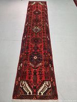 Full length view of red wool runner rug on grey floor