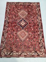 Full view of red and ivory wool rug showing central medallions and border