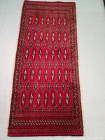 Full photo of rectangular red Turkman wool rug with geometric and tribal motifs.