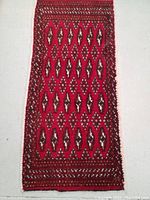 Full shot of the hand knotted Turkmen wool rug showing the vibrant red color and geometric patterns.