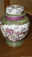 Front angle view of the porcelain jar showing floral pattern and lid.