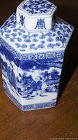 Close-up angle showing blue hand-painted figures and repeating border patterns on vase surface