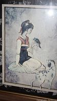 Photo of framed Chinese art print showing a kneeling woman holding a bird with a spotted dog nearby.