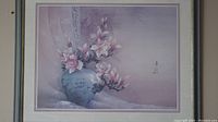 Framed artwork showing a blue vase with pink magnolia flowers on a purple background.
