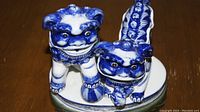 Front view of the pair of blue and white ceramic Foo lions on a round base showing their facial features and detailed glaze.