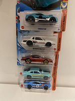 Five Hot Wheels cars in original packaging stacked vertically showing front view with details.