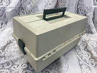 Closed view of the large vintage white Rebel 910 tackle box with black handle and latch, showing exterior condition and size.