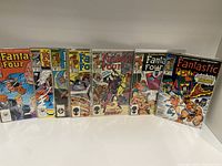 Photo of seven Fantastic Four issues from 1987, including issues 300, 301, 305-309, displayed standing on a white surface with colorful covers showing various characters and scenes.