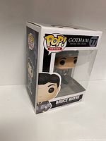 Front and side view of Bruce Wayne Pop! Heroes vinyl figure in original box with clear window showing figure inside, labeled Gotham series #77.