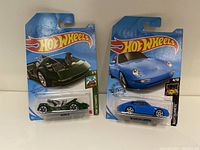Two Hot Wheels cars in original packaging: blue 1996 Porsche Carrera (Nightburnerz 4/10) and green Dewar III (HW Getaways 3/5)