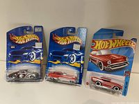 Three Hot Wheels diecast cars in original packaging displayed side by side on a white background, showing front and side details.