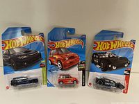 Front view of three Hot Wheels cars in blister packaging on card, models include Subaru WRX STI, Suzuki Jimny, and a black sports car.
