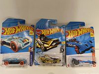 Photo showing three Hot Wheels toy cars in original packaging with blue cards, including Hot Wired model