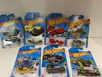 Seven Hot Wheels cars in original packaging arranged in two rows, showing full lot contents.