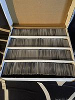 Open white cardboard box displaying four rows of unsorted Magic cards.
