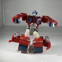 Front view of the Optimus Prime robot figure sitting, showing detailed head, chest, arms, and legs.