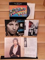 Photo of front sides of three Bruce Springsteen LP covers: Greetings from Asbury Park N.J., The River, Darkness on the Edge of Town, with vinyl record partially visible.
