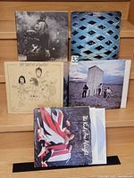Front view of five vinyl LP records placed upright, showing covers of The Who's Who's Next, The Police's Reggatta de Blanc, Alan Parsons Project, The Keys, and The Who By Numbers albums.