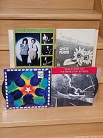 Front covers of four vinyl LP records on wood steps: Sparks 'Kimono My House', White Plains 'My Baby Loves Lovin'', Steppenwolf, Blue Öyster Cult 'The Revolution By Night'