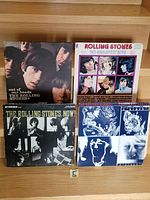 Front view of 4 vinyl LPs by The Rolling Stones showing original album cover art including portraits and text.