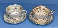 Pair of Paragon fine bone china teacups with matching saucers; one floral green, one gold filigree with crown motif