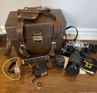 Full view of the lot including the Asahi Pentax Spotmatic SPII camera with Optex zoom lens attached, Marsand leather carrying case, flash attachment, wooden hand grip, lens caps, lens adapter ring, and manual.