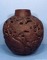 Front view of round Chinese cinnabar vase showing carved dragons and openwork design.