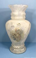Full view of the opaque white glass vase showing overall shape and cherub design.
