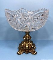 Front view of the vintage pedestal bowl showing the clear cut crystal bowl with starburst and geometric patterns and the ornate brass base.