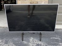 Front view of the LG 47 inch LED Smart TV showing the screen and legs on an outdoor surface.