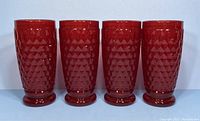 Front view of four ruby red heavy cut crystal drinking glasses in a row