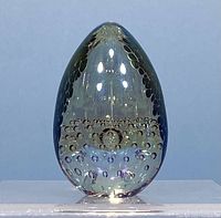 Front view of clear blown glass egg-shaped paperweight with bubble inclusions inside and iridescent reflections.