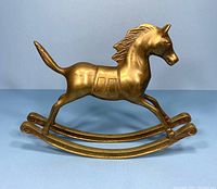 Side angle view of the brass rocking horse showing overall shape and surface condition