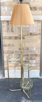 Full view of vintage brass tone floor lamp with integrated 3-tier plant stand and glass planters, beige pleated shade visible.