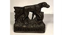 Front view of vintage cast metal pointer dog door stop with detailed sculpting and textured base.