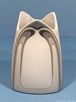 Front view of small cream ceramic vase with Art Nouveau arch design in brown, purple, and gray tones, showing unique pointed top