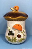Front view of the ceramic mushroom canister showing the mushroom lid and detailed mushroom design on the body.