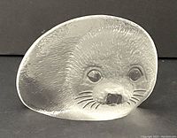 Front angle view of the clear and frosted glass baby seal sculpture with detailed etched facial features and textured fur patterns.