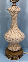 Full view of the curvaceous Murano glass lamp with gold and white swirl pattern on brass base.