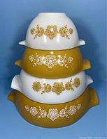 Stacked view of four Pyrex Cinderella bowls alternating white and gold-yellow, showing Butterfly Gold floral decals.