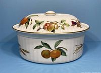 Front view of lidded casserole showing colorful fruit and botanical motifs with gold trim