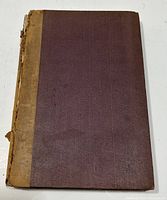 Photo of book cover showing purple cloth and tan spine with detached spine and visible wear.