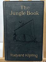 Front cover showing dark green embossed board with gilt title, author name, and sailboat design
