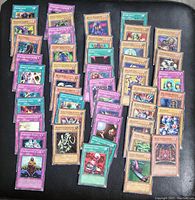 Multiple Yu-Gi-Oh cards spread out showing various monster, spell, and trap cards with wear and bends visible.