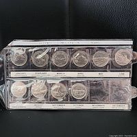 Full view of coin set in plastic case showing 11 Canadian 25 cent coins commemorating 125 years of Confederation with province/territory depictions and month labels.