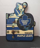 Full view of the clock showing the hockey player in blue and white uniform skating and the Toronto Maple Leafs logo on a hockey puck shape next to clock face.