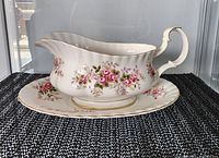 Gravy boat with underplate showing floral Lavender Rose pattern and gold rims from front angle